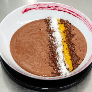 Natilla vegana de chocolate al 70% de cacao con coulis de mango y coco.